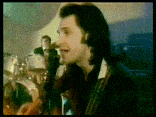 a man is singing into a microphone in front of a drum set