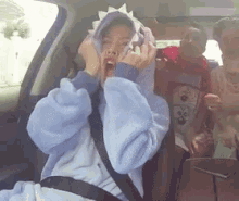 a woman wearing a dinosaur costume is sitting in a car with her mouth open .
