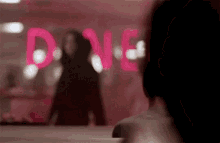 a woman is looking at her reflection in a mirror with the word love painted on it .