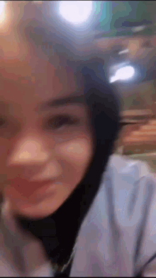 a blurry picture of a woman wearing a hijab and smiling