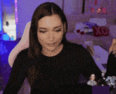 a woman in a black shirt is sitting in front of a couch with a xoxo pillow