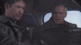 two men are sitting in a car with the words and written on the bottom