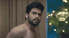 a shirtless man with a beard is pointing at something with his finger .