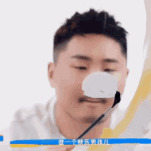 a man is holding a brush in front of his face with chinese writing behind him