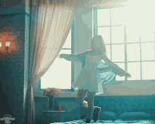 a woman in a white dress is dancing on a bed