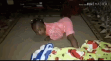 a little girl in a pink shirt is crawling on the floor next to a blanket .