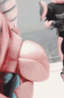 a close up of a pink robot 's arm with a person standing behind it