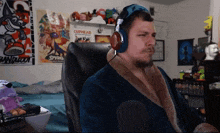 a man wearing headphones sits in a chair in front of a cuphead poster