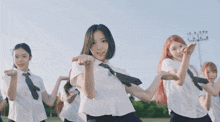 a group of girls in school uniforms and ties are dancing in a field