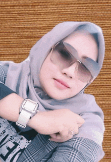a woman wearing a hijab and sunglasses has the letter h on her shirt
