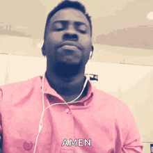 a man wearing headphones and a pink shirt with amen written on it