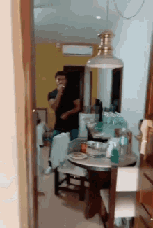 a man in a black shirt is smoking a cigarette in a room