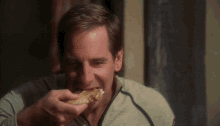 a man is eating a piece of bread while wearing a military uniform .