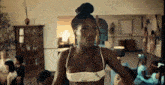 a woman in a white bra is standing in a room with a bun on her head .