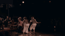 three men are dancing on a stage with a crowd watching