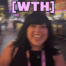 a woman is smiling in front of a sign that says wth