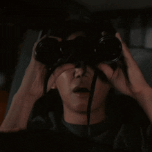 a person looking through a pair of binoculars with a surprised look on their face