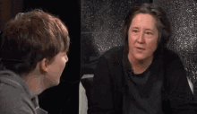 a woman and a boy are talking to each other in a dark room .