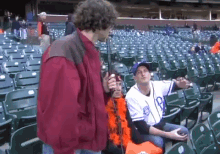 a man in a red jacket is standing in a stadium with people sitting in the seats