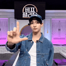 a man wearing a hat and a denim jacket stands in front of a sign that says hit on it