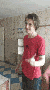 a young man in a red shirt is giving a thumbs up .