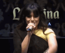 a woman singing into a microphone in front of a sign that says lina a