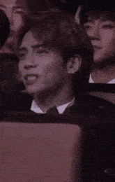 a man in a suit and tie is sitting in a row of people .