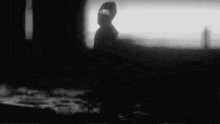a black and white photo of a person walking in the dark
