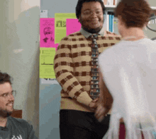 a man in a plaid sweater and tie talks to a woman in a white dress