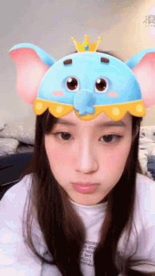 a girl wearing a blue elephant hat with a crown