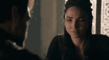 a man and a woman are looking at each other in a dark room . the woman is wearing dreadlocks .