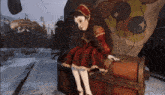 a doll in a red dress sits on a trunk in front of a carnival sign