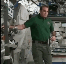 a man in a green shirt is standing in a room with a sign that says ' emergency exit '