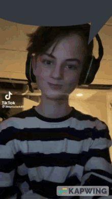 a young man wearing headphones and a striped shirt is on a tiktok video ..