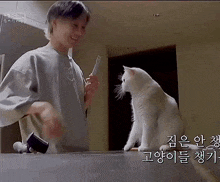 a man is playing with a white cat in a kitchen