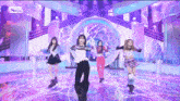 a group of girls are dancing on a stage with a pop logo in the corner
