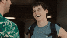a young man with curly hair wearing a blue t-shirt with the letter o on it