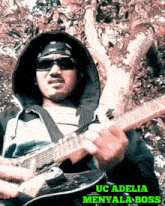 a man playing a guitar with the name uc adelia
