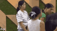 a group of women are standing next to each other in a room with a green wall .