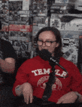 a woman in a red temple sweatshirt is talking into a microphone