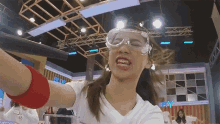 a woman wearing goggles is making a funny face while holding a glass of water .