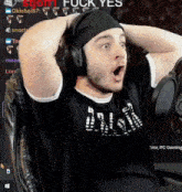 a man wearing headphones and a headband is sitting in a chair with his hands on his head .