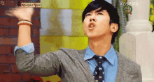 a man in a suit and tie is making a funny face with his hand in the air