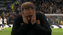 a man covering his ears on a soccer field with umbro written on his sleeve