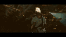 a man singing into a microphone while playing a guitar with a strap that says ' x ' on it
