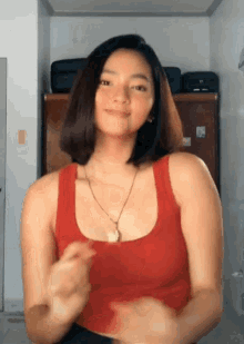 a woman in a red tank top is standing in a room .