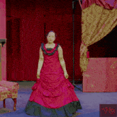 a woman in a red dress stands in front of a red curtain and a sign that says ho