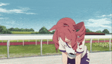 a girl with red hair is standing on a track with a white fence in the background