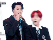 a man singing into a microphone next to another man