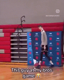 a man is walking on a basketball court with the words this guy at my bros game written on the floor .
